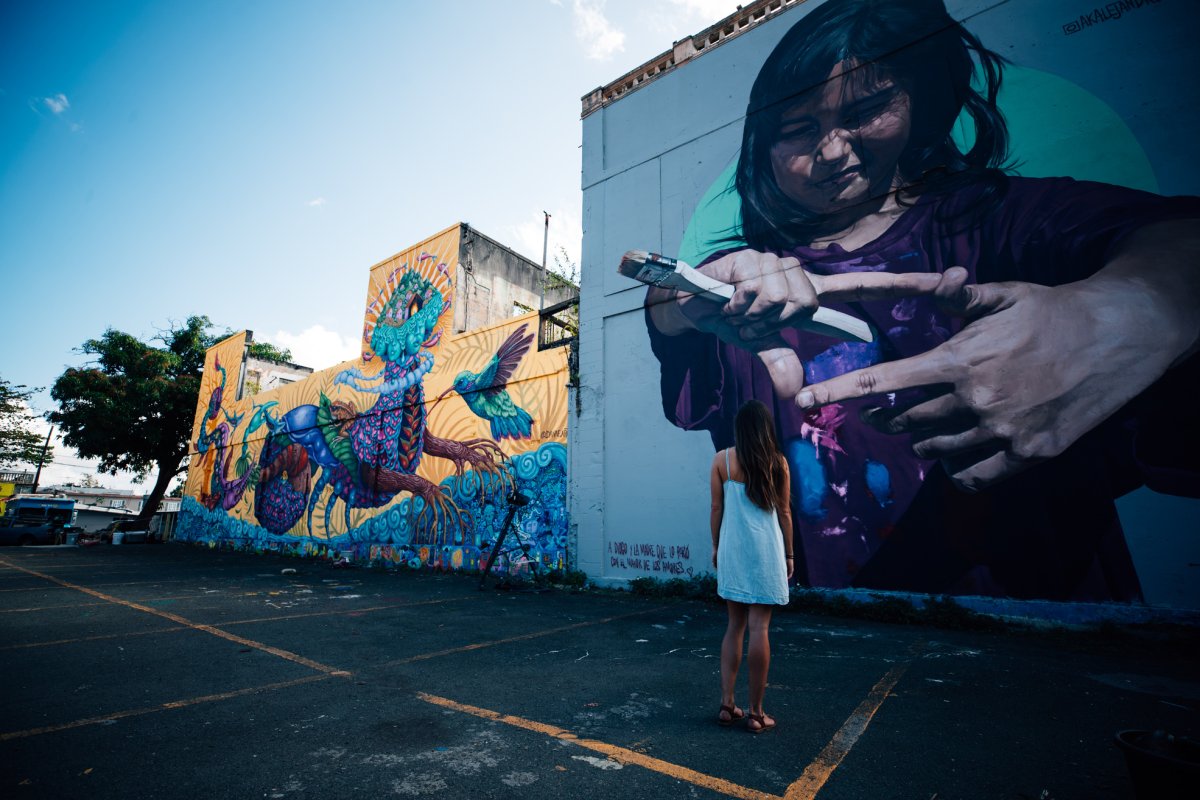 A woman looks up at a large mural on the side of a building in the Santurce area