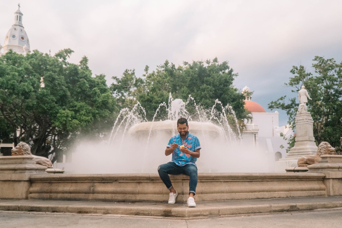 A man sits on the steps of a fountain in the Plaza las Delicias in Ponce.