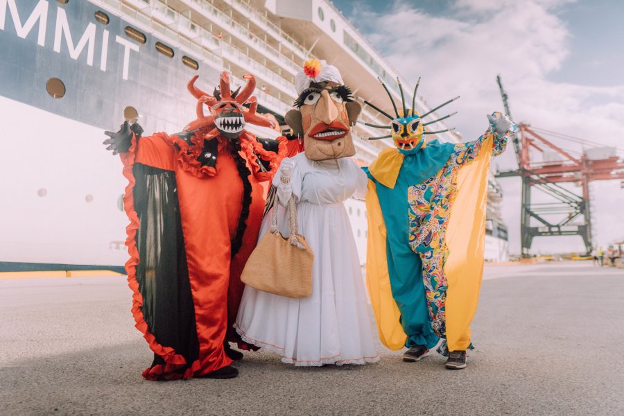 Local vejigantes performers stand in front of a cruise ship at the Ponce Cruise Port.