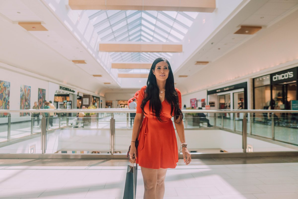 A woman walks through the mall with a bag in her hand