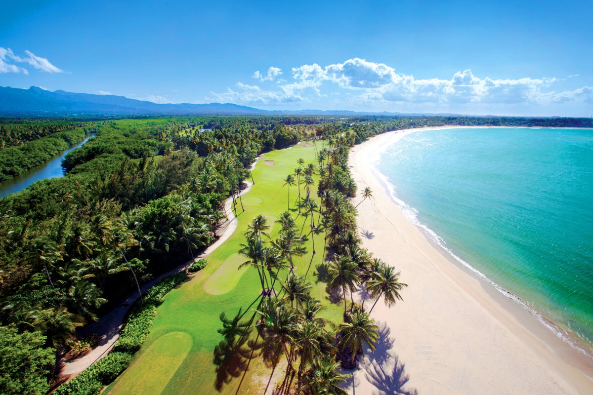 An aerial view of the St. Regis Bahia Beach golf course, nestled between the ocean and the mountains.