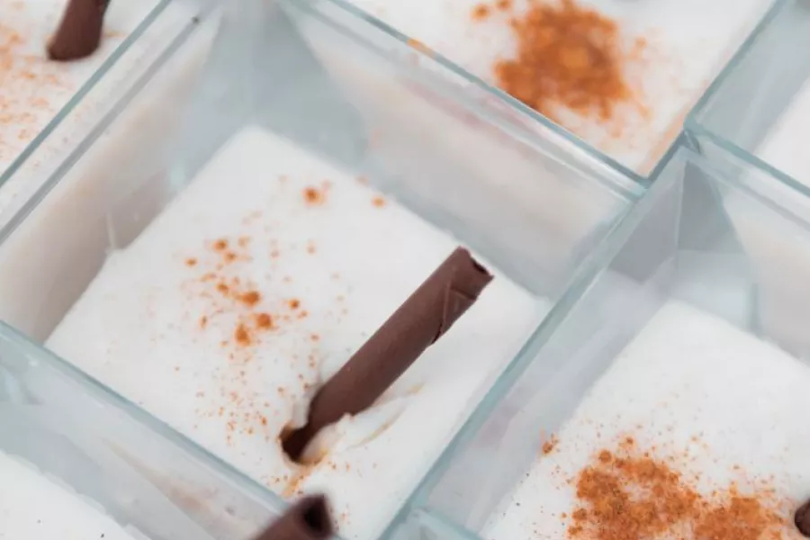 Cups of tembleque, a traditional Puerto Rican coconut dessert, garnished with cinnamon sticks.