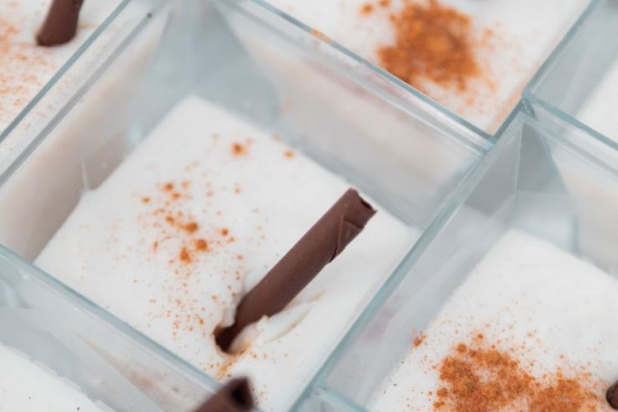 Cups of tembleque, a traditional Puerto Rican coconut dessert, garnished with cinnamon sticks.