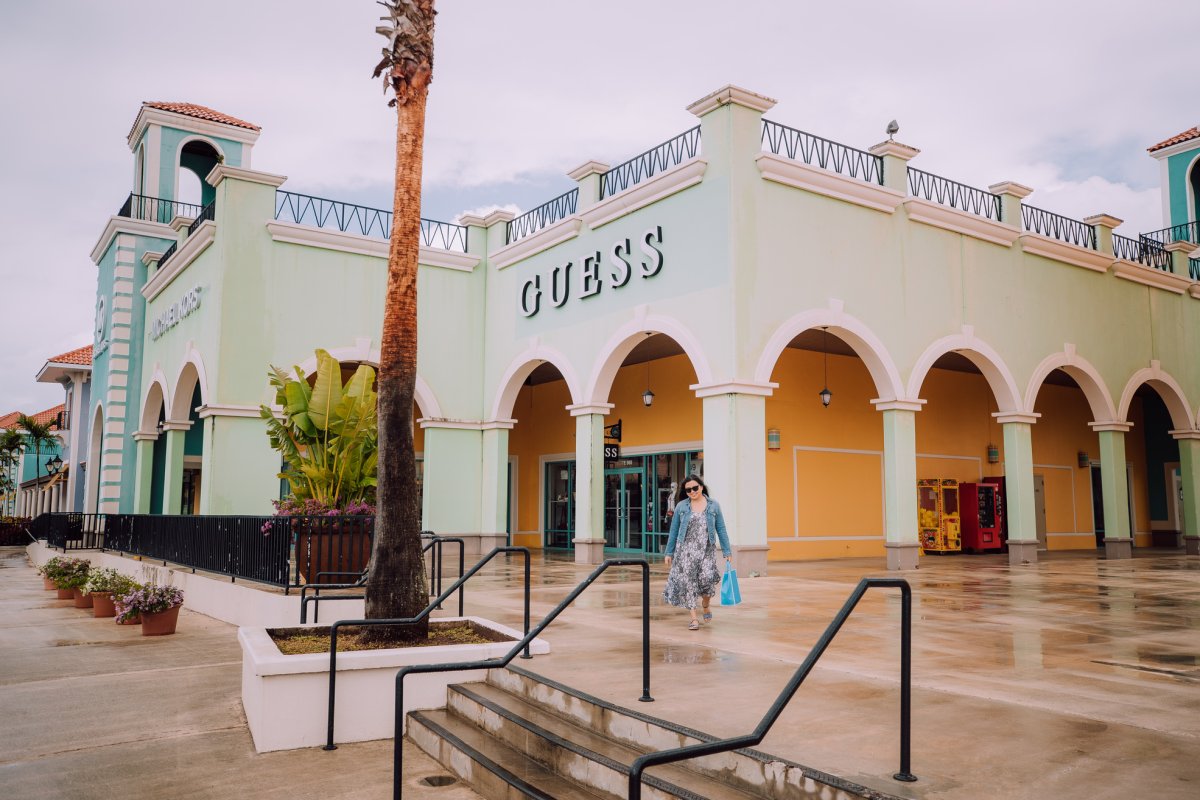 A woman walks away from a store with a bag in hand