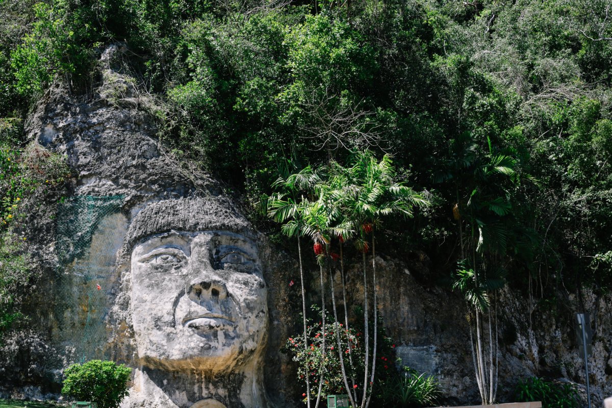 A massive face carved into the side of a steep stone cliff 