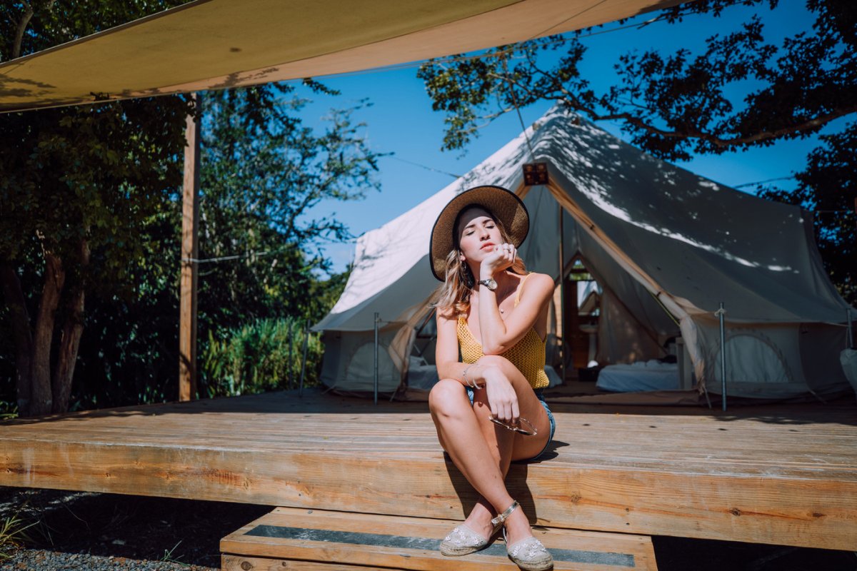 A girl sits in front of a camping tent at Pitahaya Glamping.