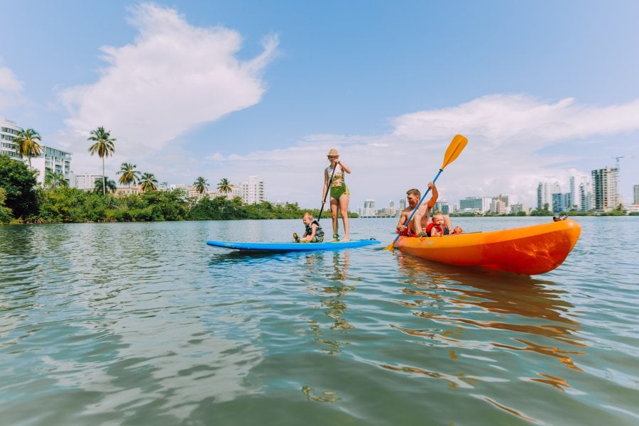 A family of four enjoying their kayak and paddle board at the Condado Lagoon.