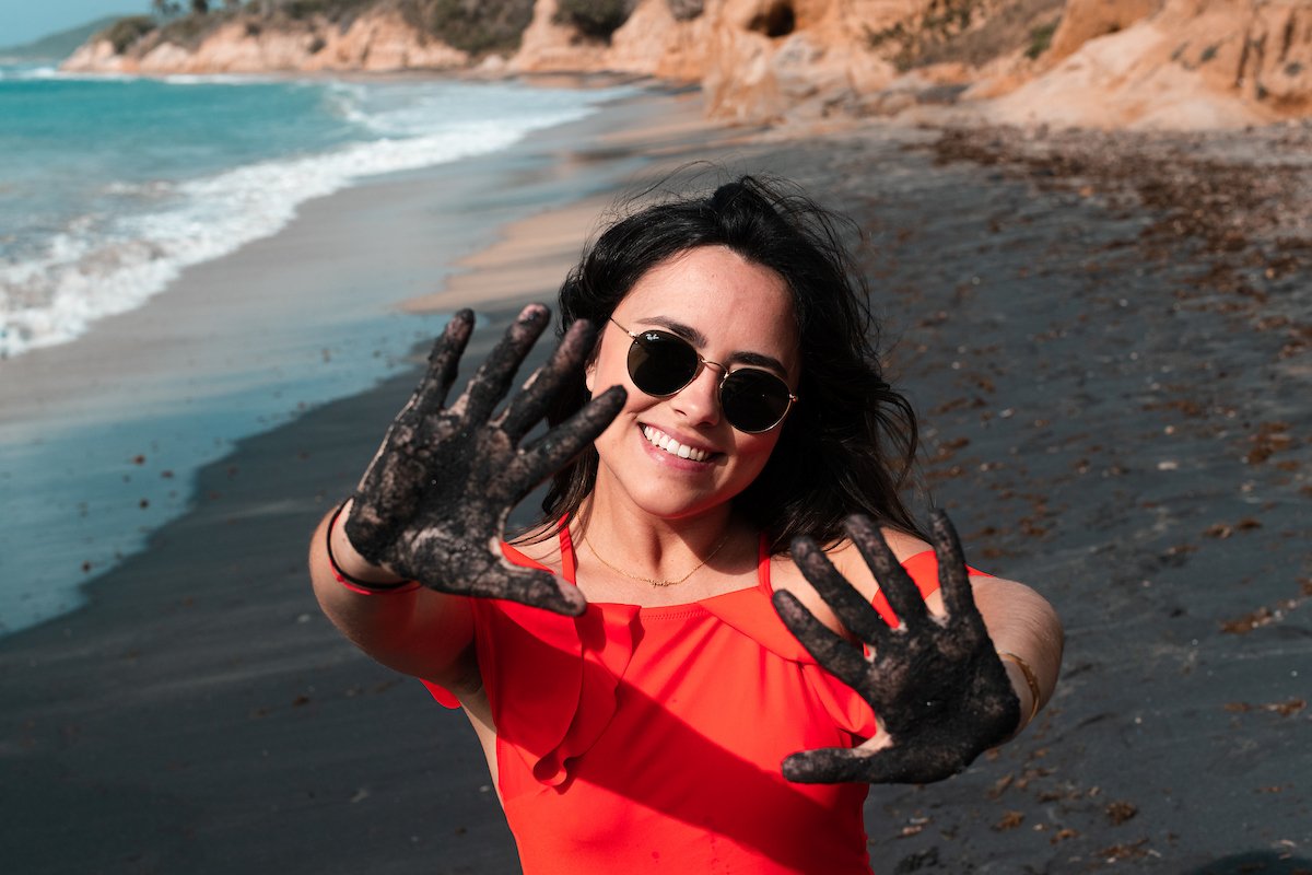 Woman plays with black sand at Playa Negra in Vieques