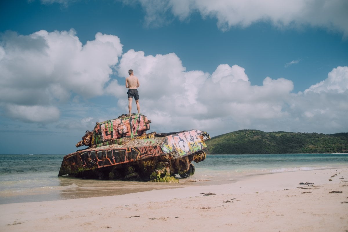 Man standing atop an abandoned Navy tank in the shore of Flamenco Beach in Culebra.