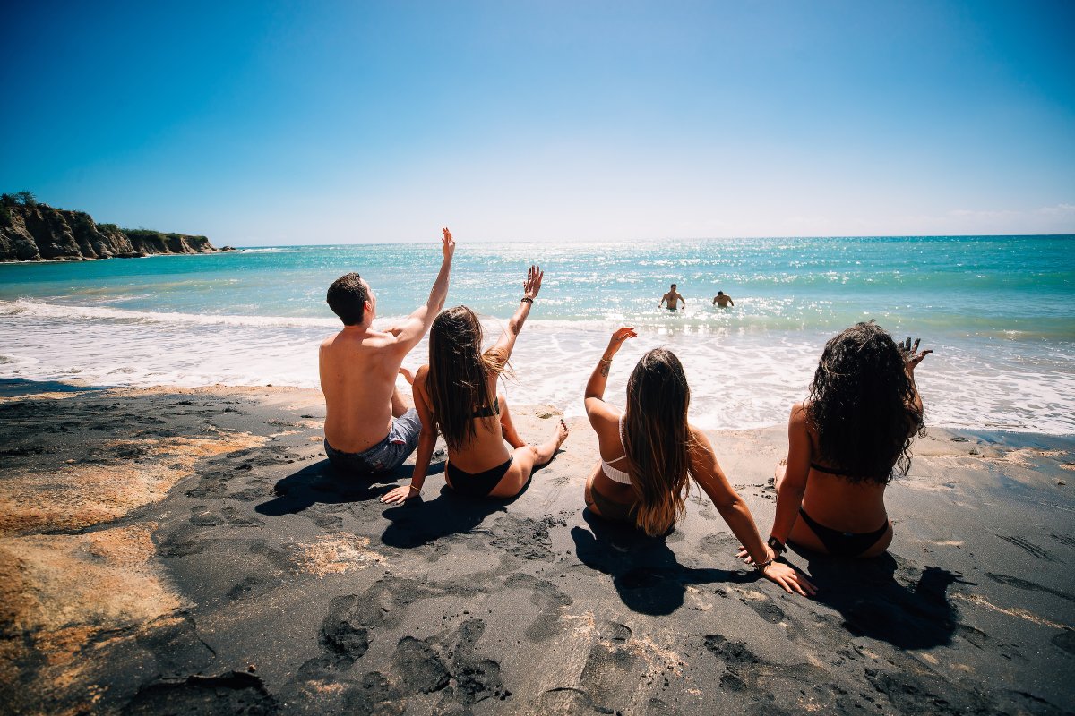 Un grupo de hombres y mujeres disfrutan de las aguas turquesas en la Playa de Arena Negra en Vieques.