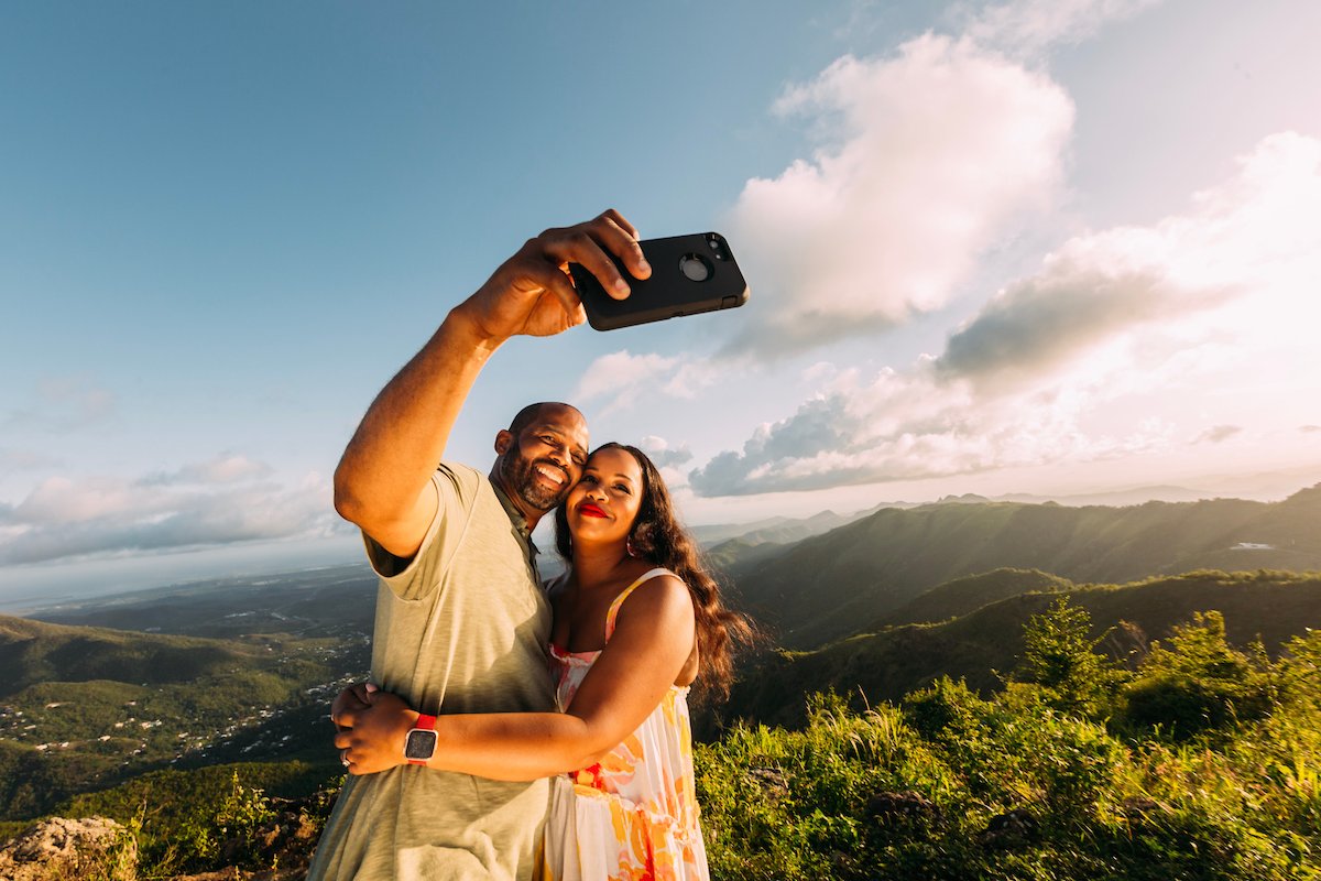 A couple takes a selfie with a backdrop of lush mountains in Puerto Rico's central region.