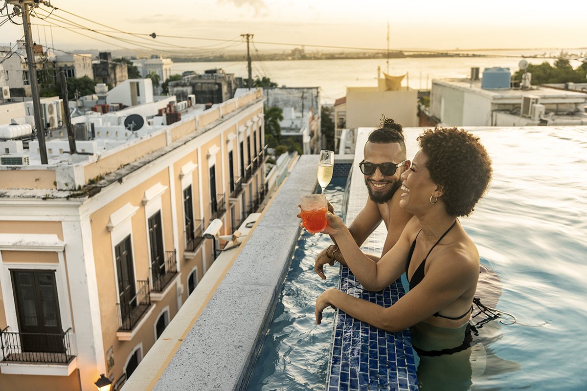 A couple enjoys cocktails in a rooftop pool in Old San Juan