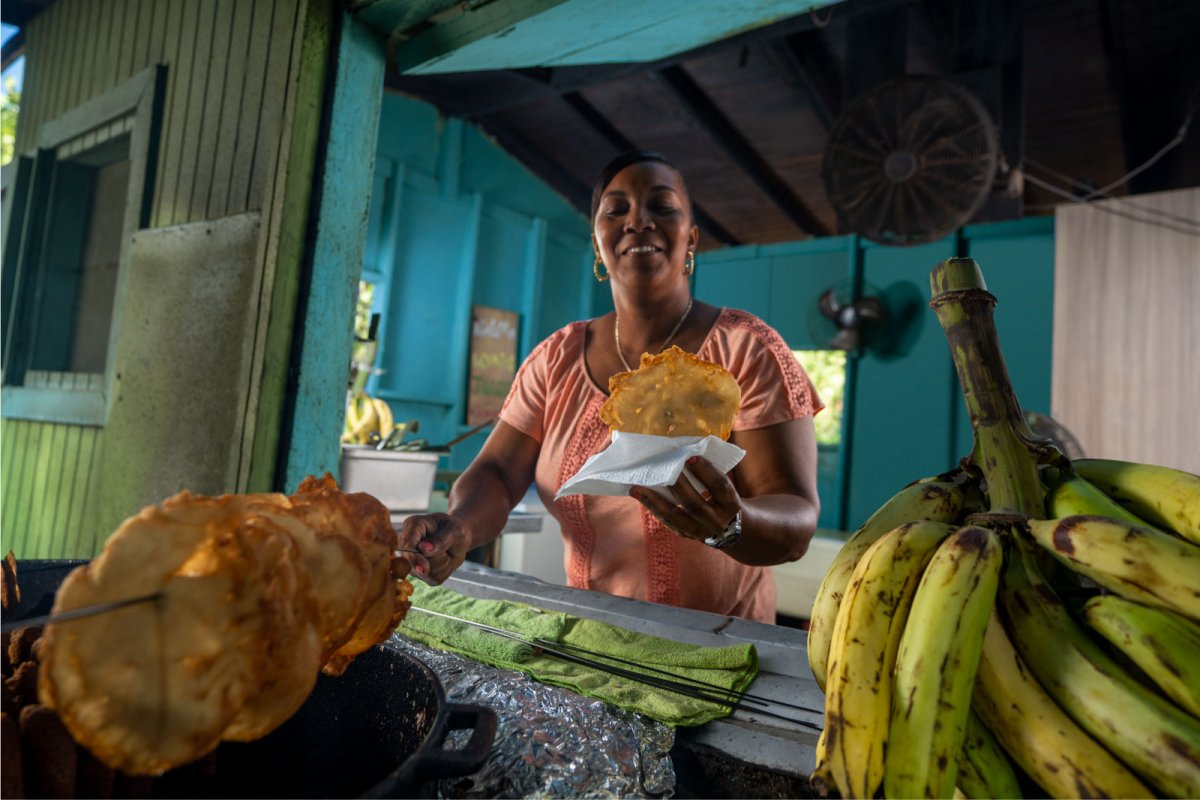 Una mujer sirve un buñuelo recién frito en un quiosco en Pinones, Puerto Rico