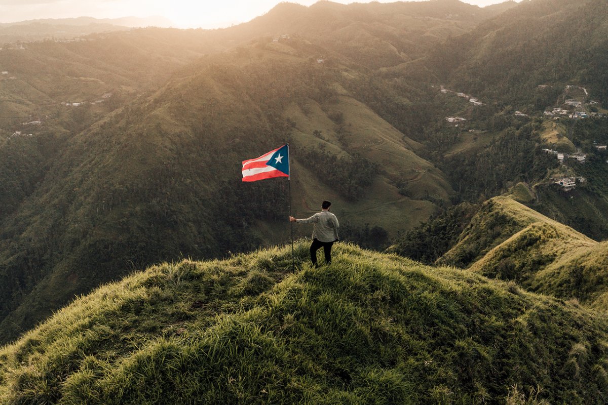 man in the mountains with Puerto Rico flag
