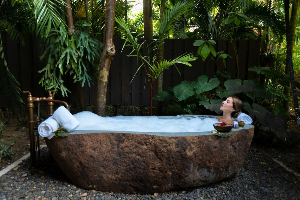 A woman relaxes in a stone bathtub at Spa Botanico.