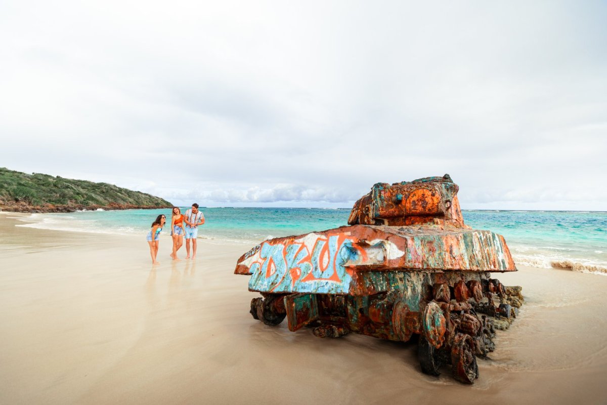 A group of friends walk toward the iconic military tank at Flamenco Beach in Culebra, Puerto Rico.