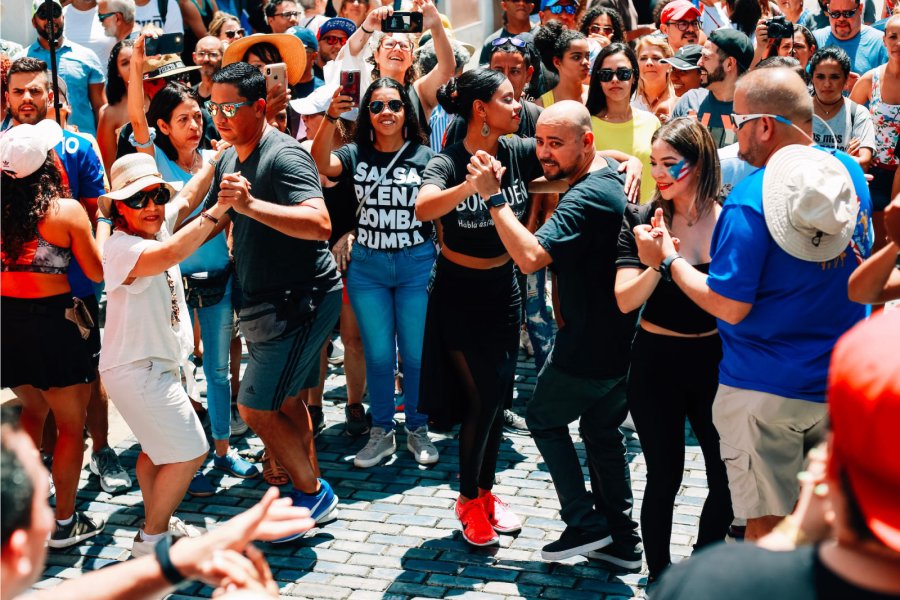 A joyful crowd participates in salsa dancing in the streets of historic Old San Juan, a lively display of Puerto Rican culture and community spirit.
