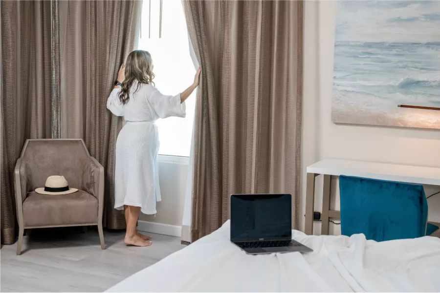 A woman stands in her guest room at the Hyatt Centric San Juan - Isla Verde, looking out the window.