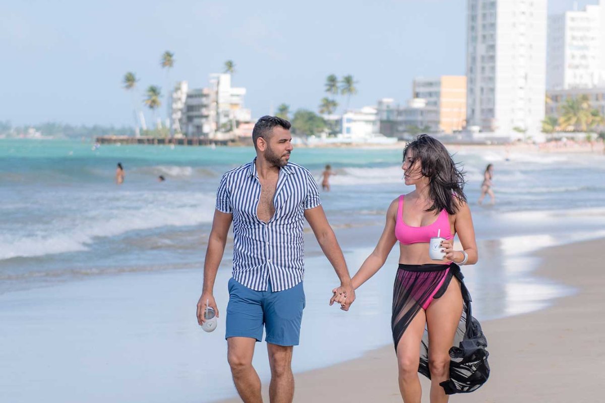 A couple holding hands strolls on a beach near the Verdanza Hotel in Carolina, Puerto Rico.