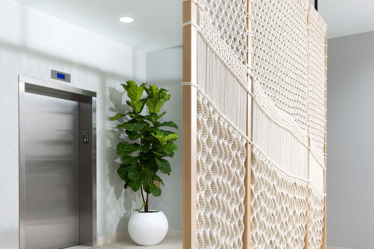 A divider wall made of macrame knots by artist Aleida Carde stands before a bank of elevators at the Residence Inn by Marriott San Juan Isla Verde.