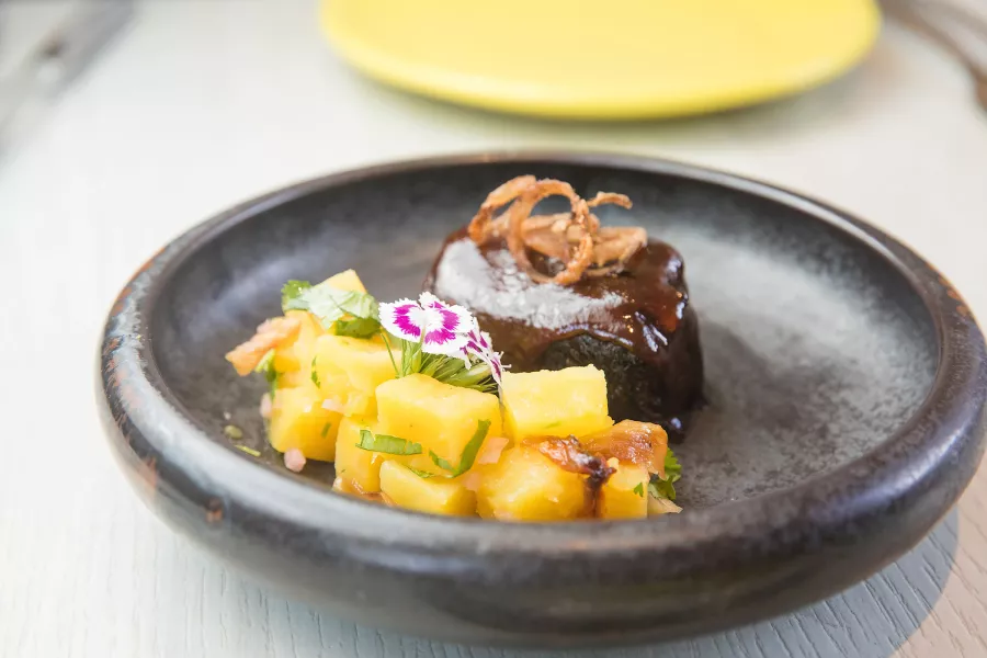 Chef Mario Pagan's Guava BBQ Short Rib sits on a charcoal gray plate.