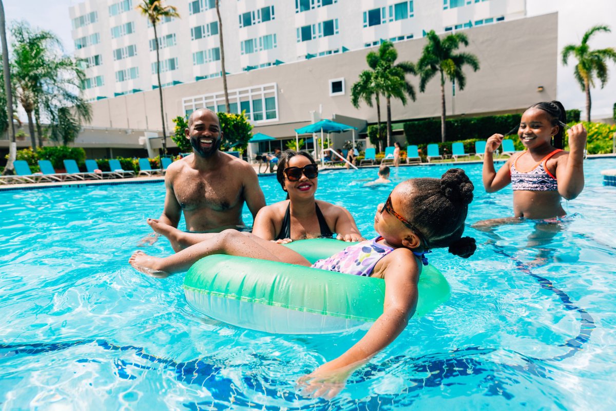 A family with two parents and two kids plays in a resort pool in Puerto Rico.