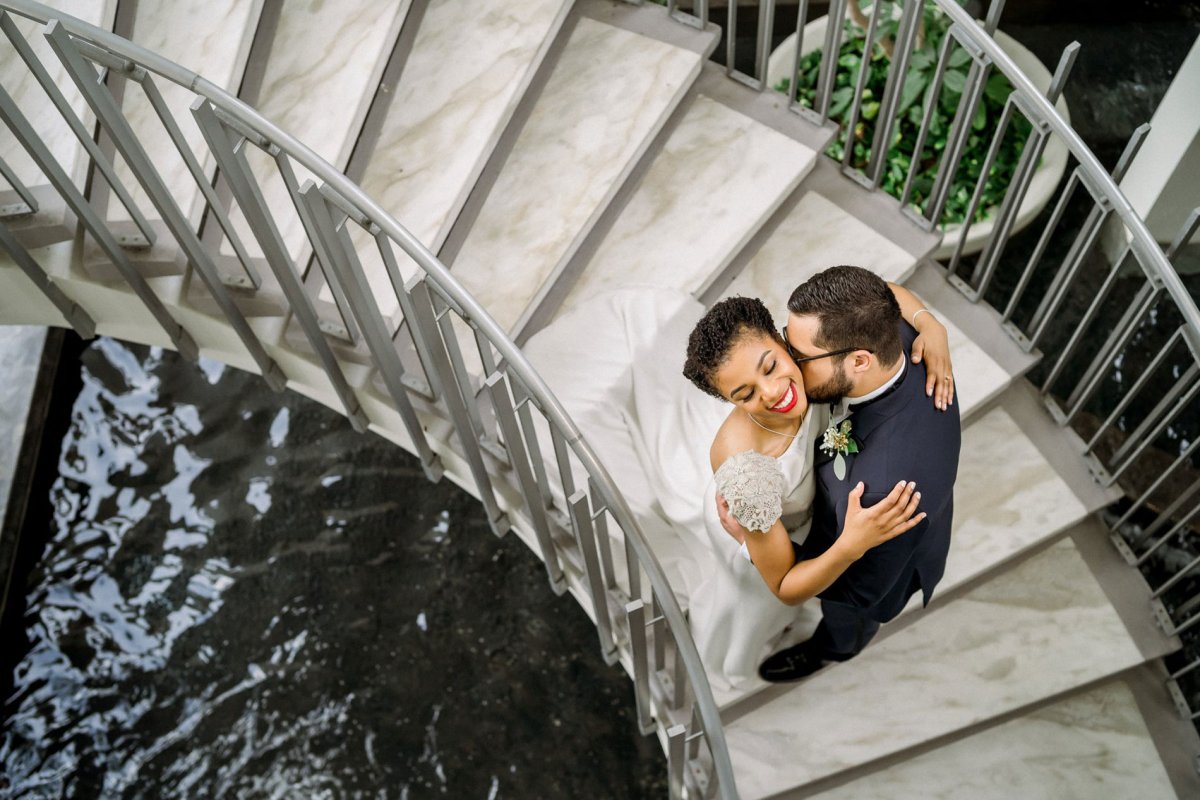 Overhead wedding photo of a couple embracing on a spiral staircase over water at La Concha Renaissance Resort. San Juan, Puerto Rico.