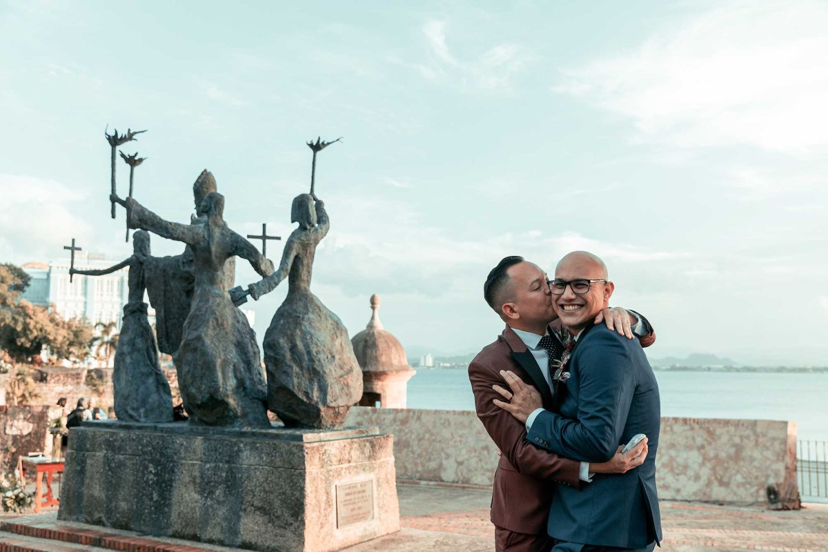 An LGBTQ couple embrace on their wedding day in front of La Rogativa in San Juan, Puerto Rico