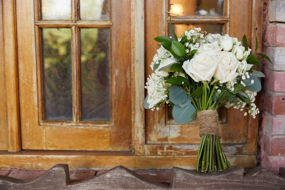 A wedding bouquet of white flowers leans against a wooden window at a wedding venue in Puerto Rico.