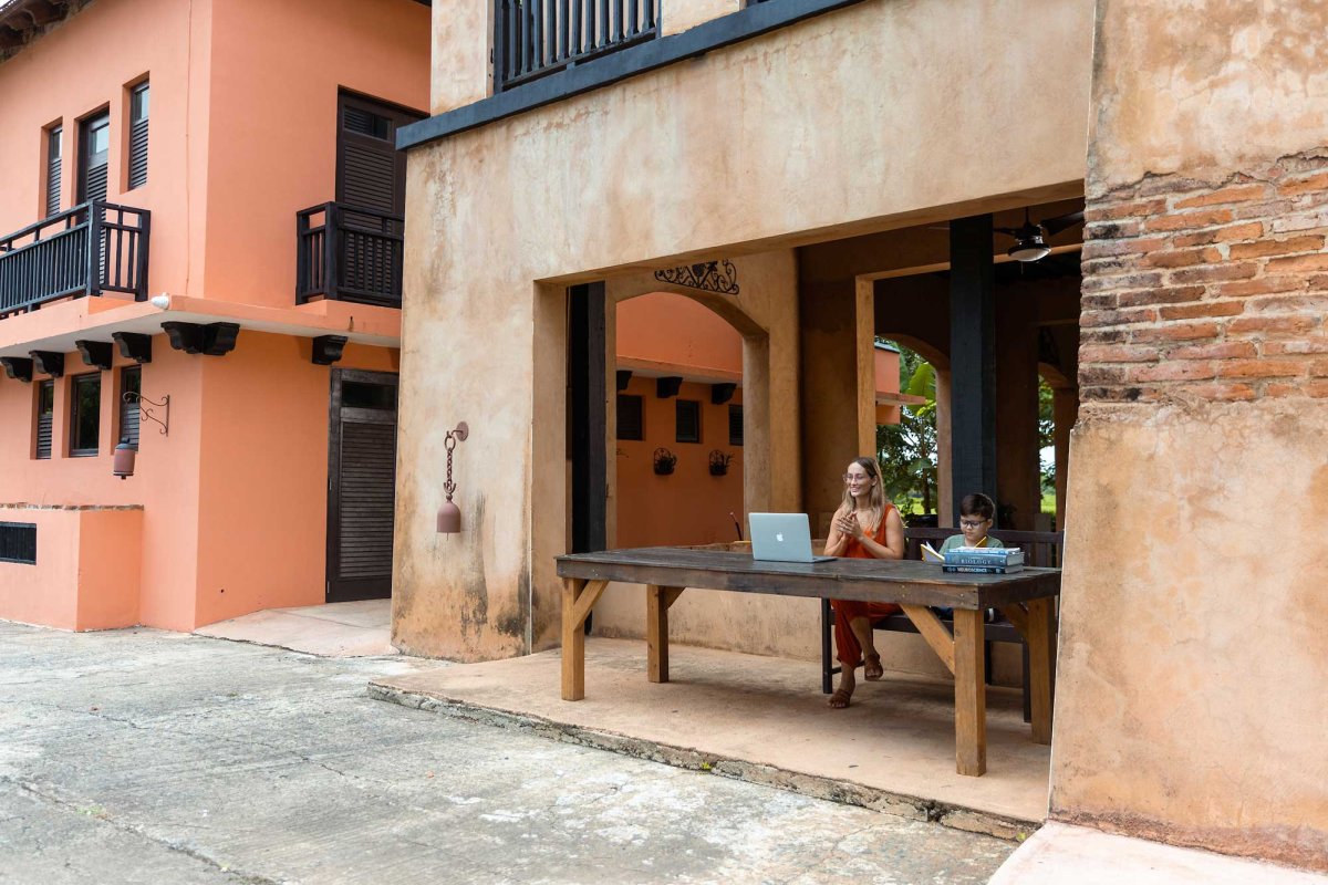 A woman and young boy sit at a desk overlooking a historic street in Puerto Rico.