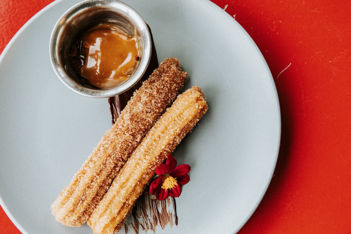 Two churros paired with a chocolate dipping sauce.