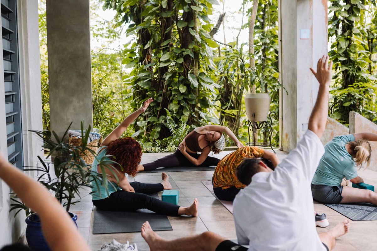 A group of people participate in a yoga class on a lush outdoor patio at Dos Aguas, a boutique hotel in Río Grande, Puerto Rico.