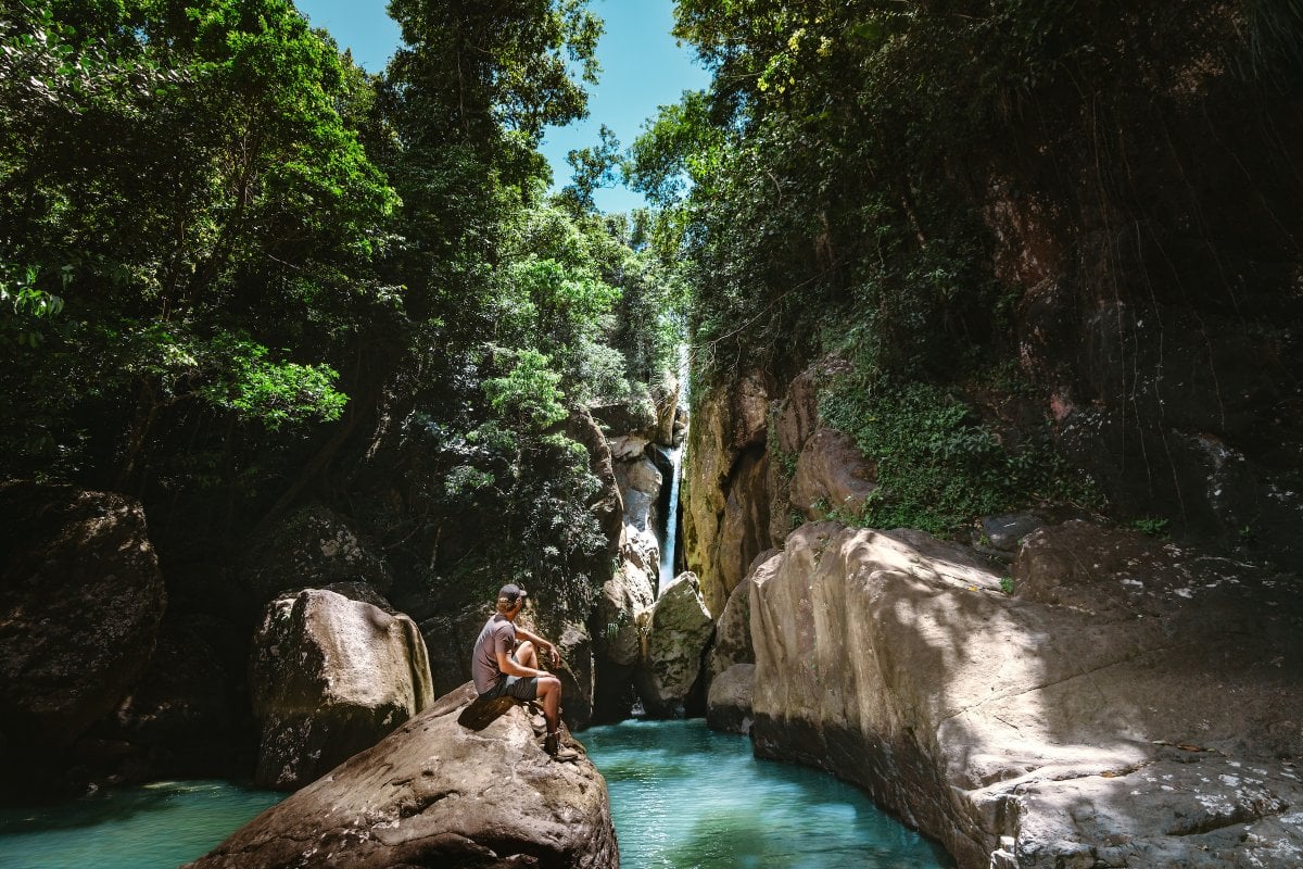 Hiker standing in front of a waterfall in El Yunque National Forest, Puerto Rico rainforest adventure.