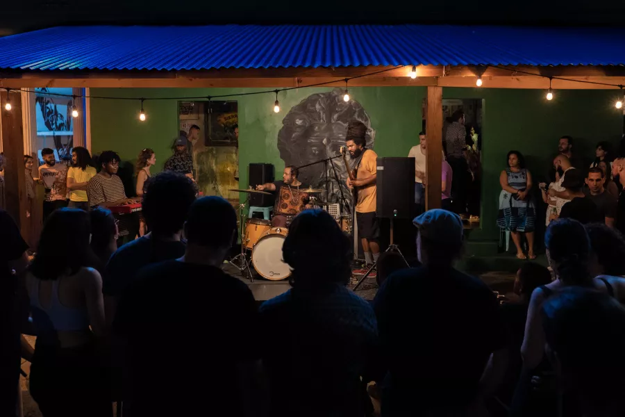 A group of people watching a musical performance in a backyard.