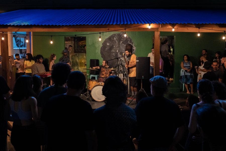 A group of people watching a musical performance in a backyard.
