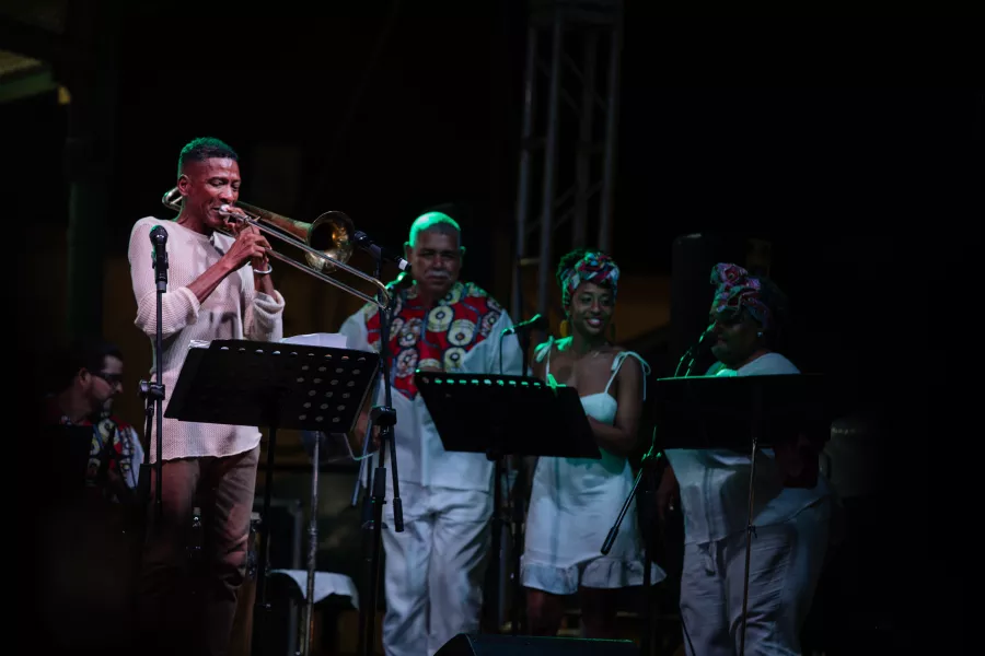 Grupo de artistas en escena con pleneros y trompetas