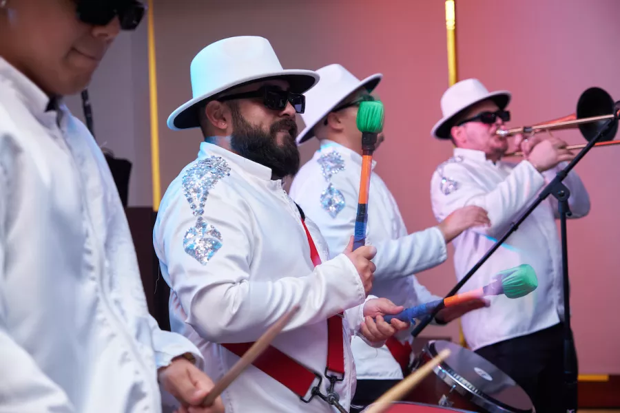 Grupo de músicos de jazz latino combinando instrumentos de viento y percusión.