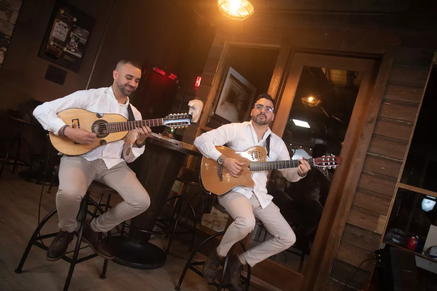 Dos personas tocando la guitarra y el cuatro, instrumentos tradicionales puertorriqueños