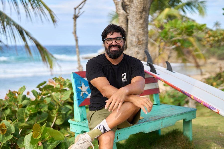 Héctor Varela, Program Manager at Surfrider, seated in front of the beach.