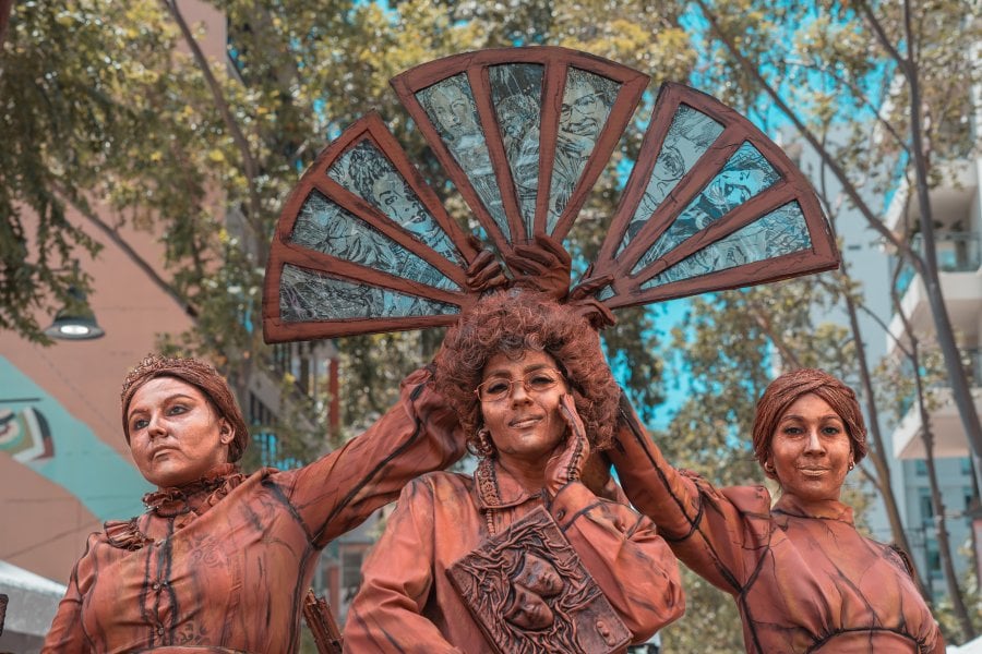 Artists dressed as living statues with a decorated fan at La Campechada, a vibrant cultural festival in Puerto Rico.