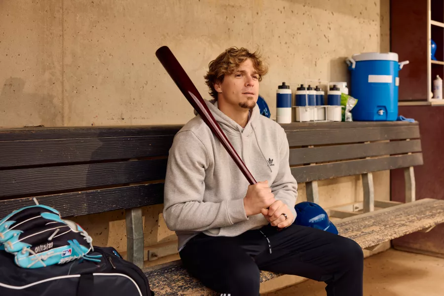 Kike Hernandez holds a bat in a baseball dugout. 