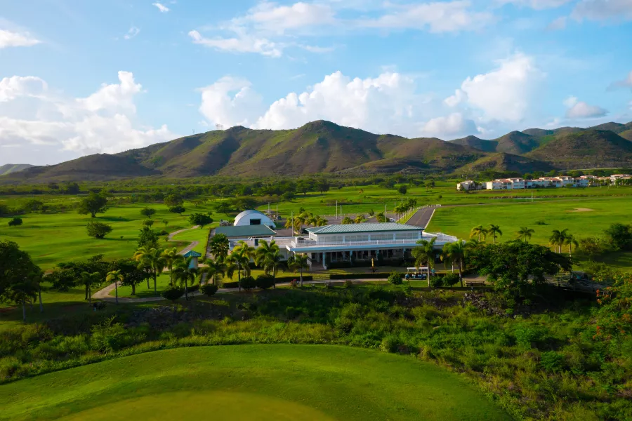 Golf course surrounded by mountains and clubhouse at El Legado in Guayama..