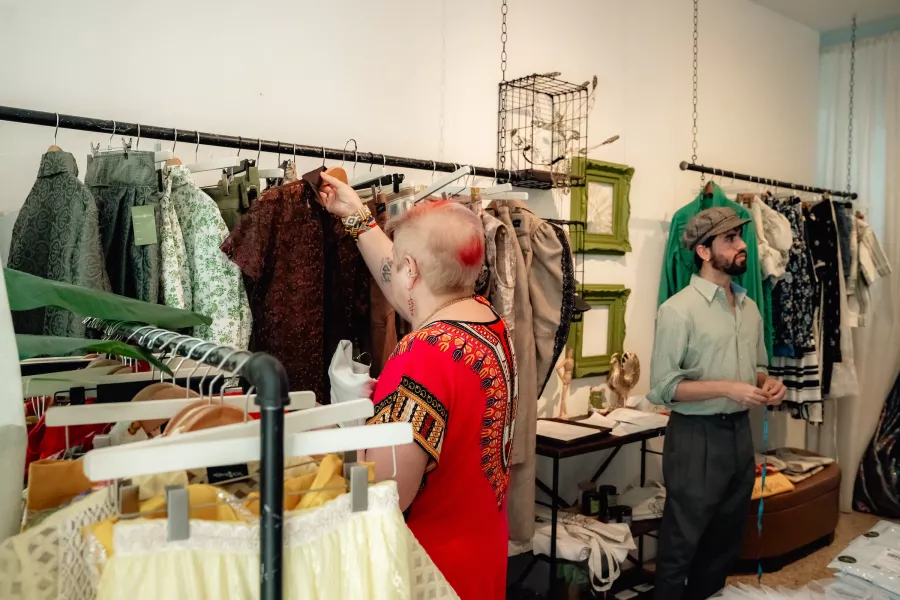 Interior of a fashion atelier with clothing racks and a person selecting garments
