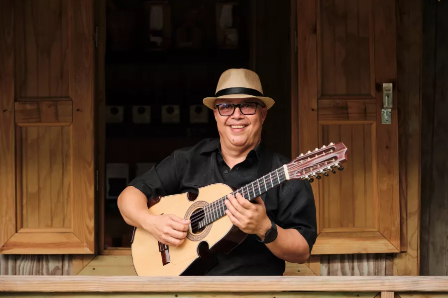 Un guitarrista con su instrumento en mano y una sonrisa en su cara.