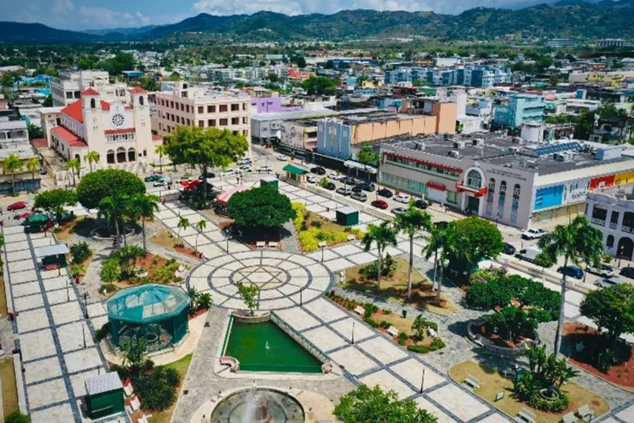 Aerial view of downtown Caguas featuring the central plaza, colorful buildings, and surrounding green mountains in Puerto Rico.