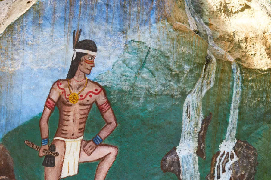 Illustration of a Taíno figure painted on a rock at Parque Ceremonial La Cueva del Indio in Puerto Rico, depicting Indigenous culture, ceremonial traditions, and a settlement landscape.