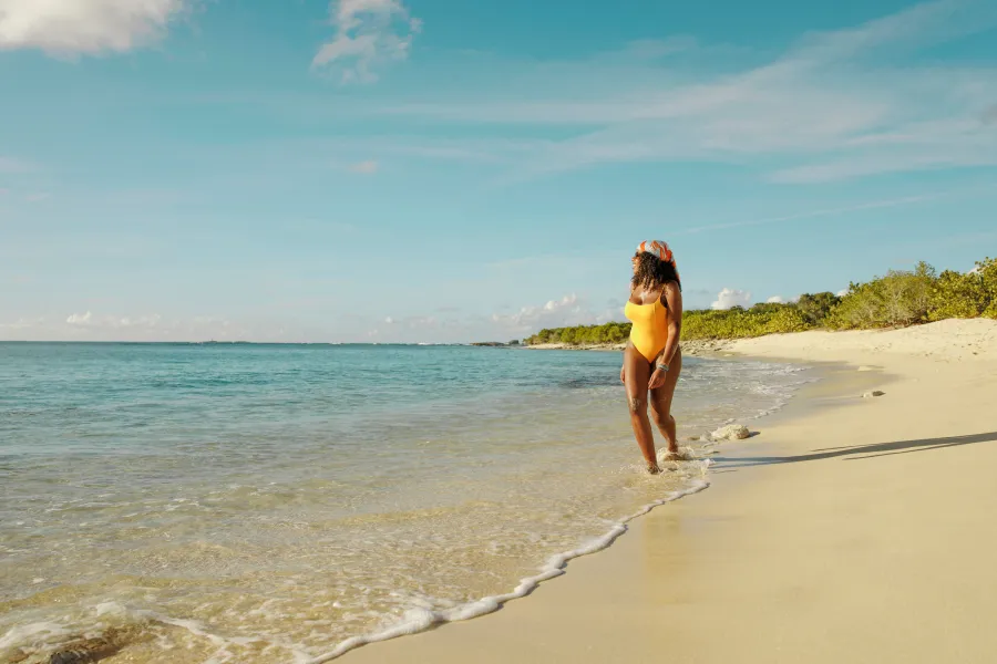 Woman walking along the shoreline of a sandy beach in Puerto Rico on a sunny day.