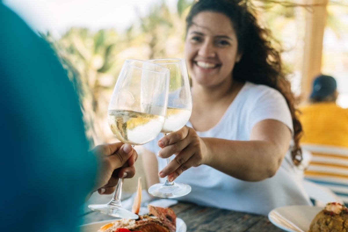 Two people dine on a patio, clinking wine glasses.