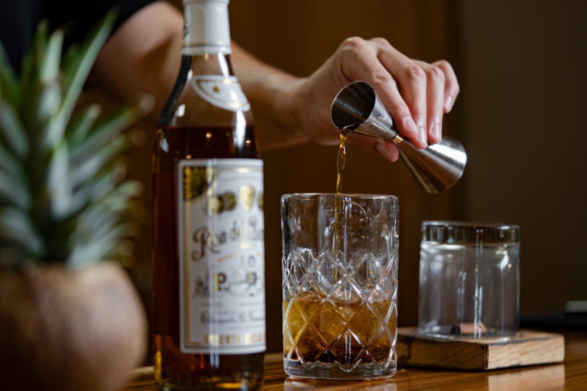 A bartender pours a shot of Ron del Barrilito into a glass