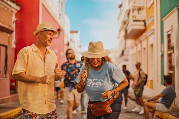 Couple dancing through the streets of Old San Juan during Fiestas de la Calle San Sebastián, surrounded by colorful buildings and festival crowds.